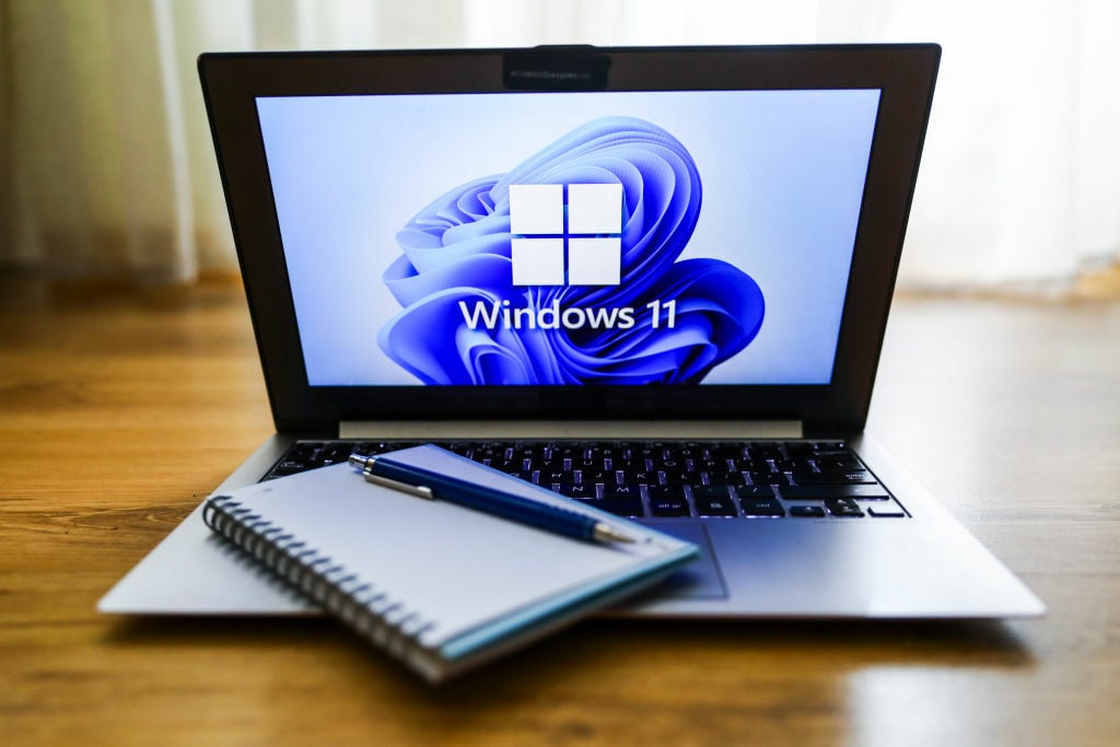 Microsoft Windows 11 laptop with notepad on keyboard