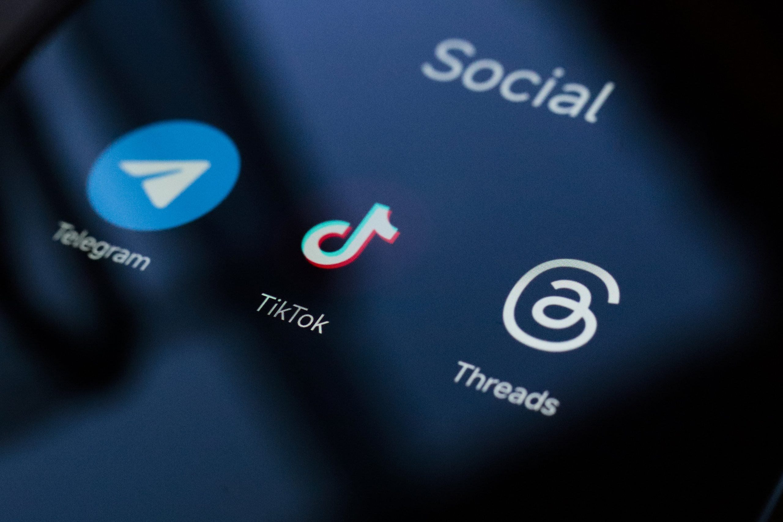 A close up of a phone screen showing the Telegram, TikTok, and Threads apps. 