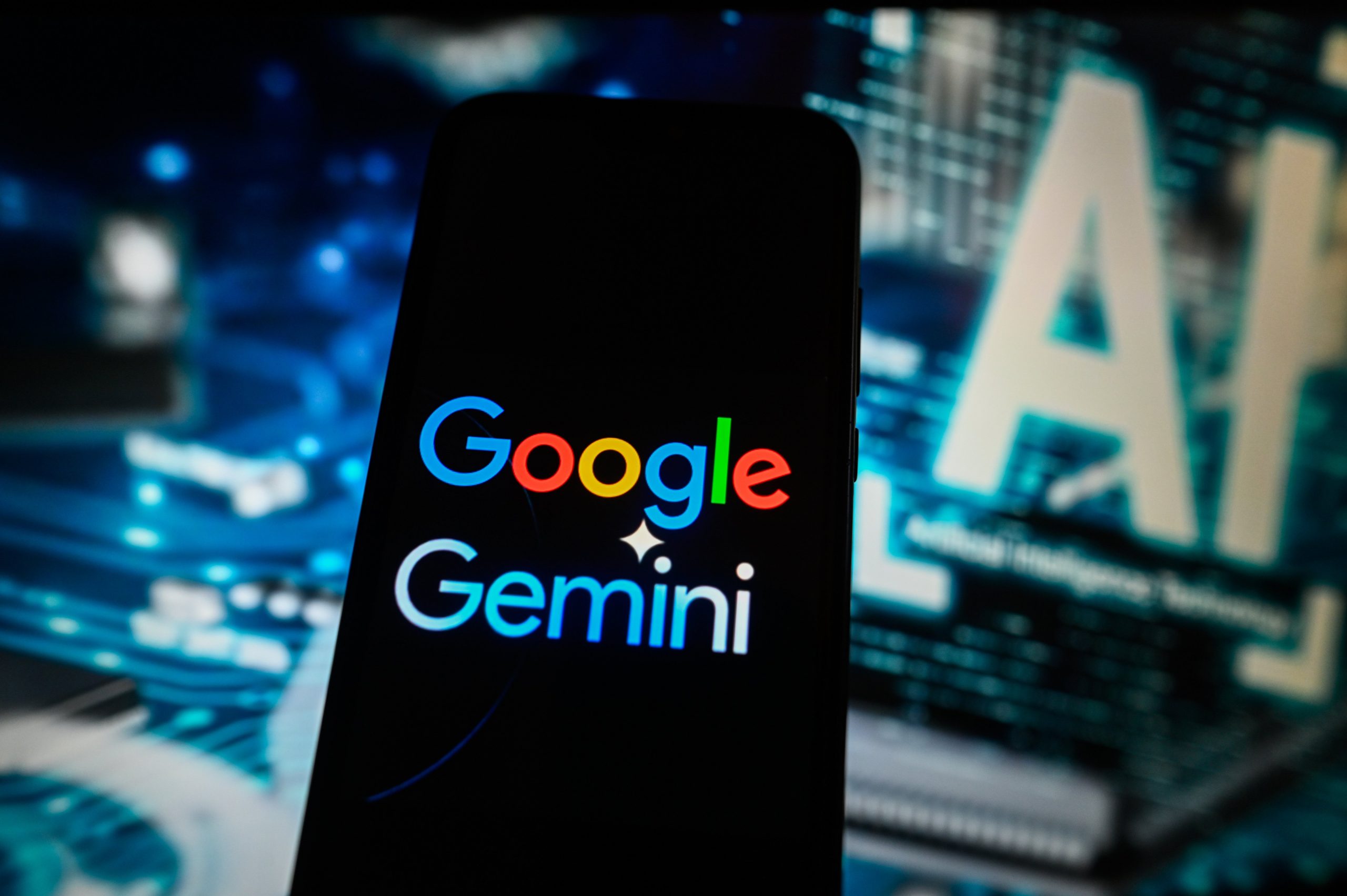 A Google Gemini logo is displayed on a smartphone with Artificial Intelligence symbol on the background.