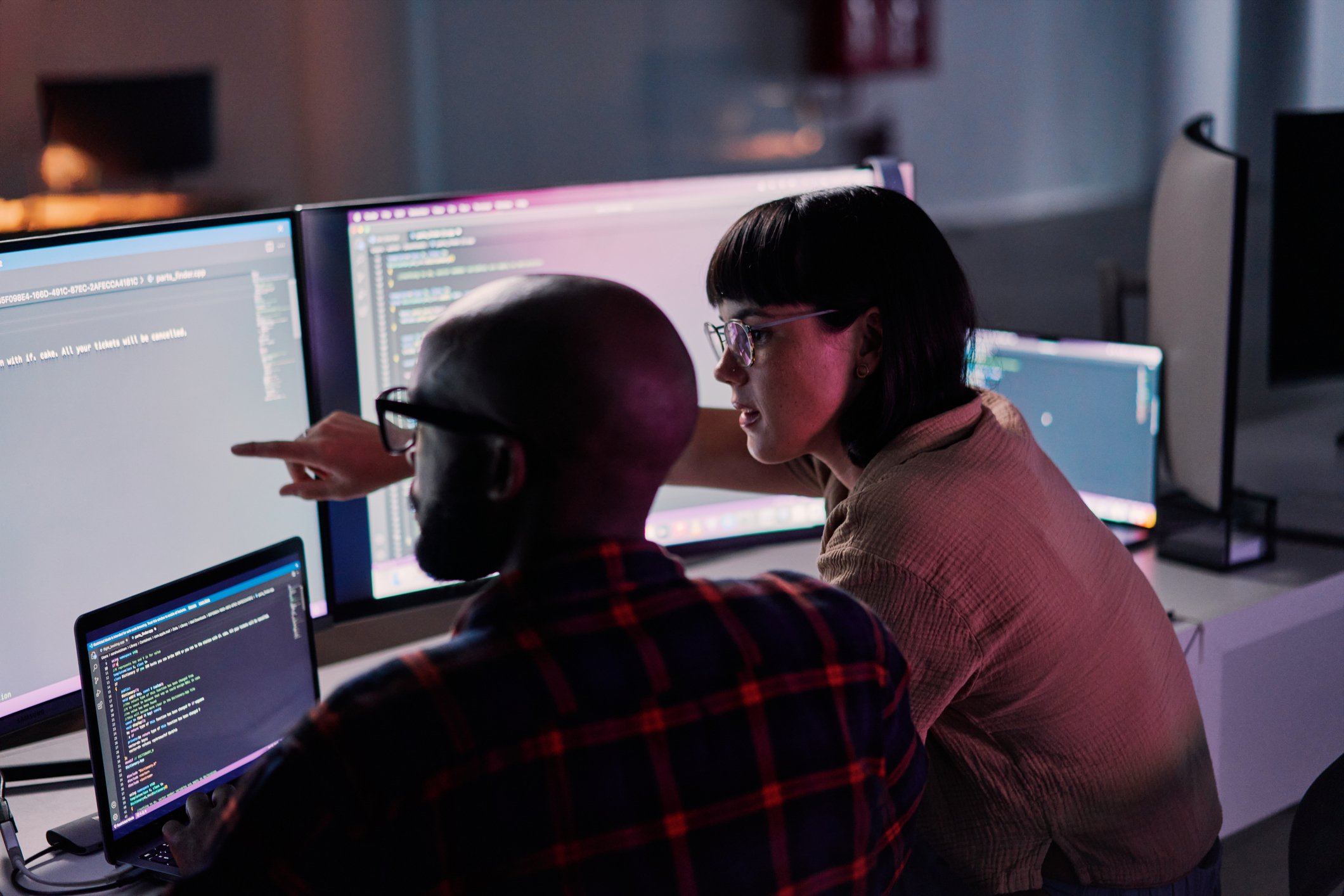 man and woman learning to code in front of computer screens