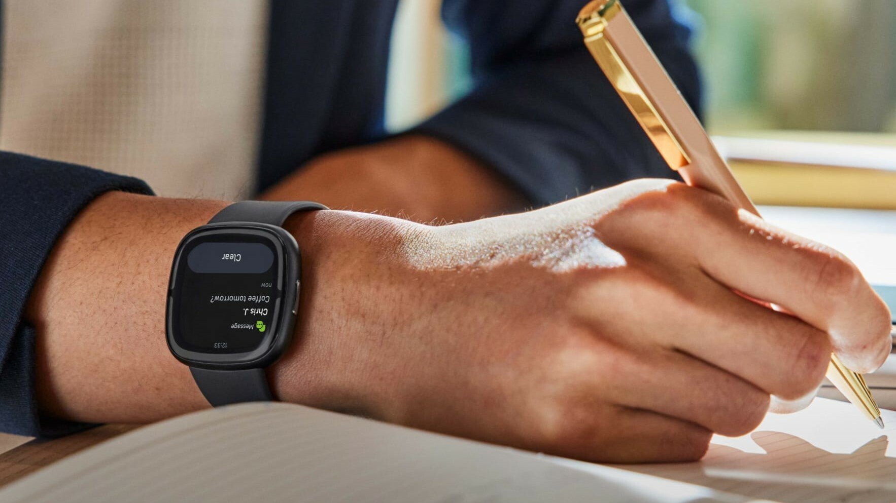 Fitbit Sense 2 on a hand holding a pen