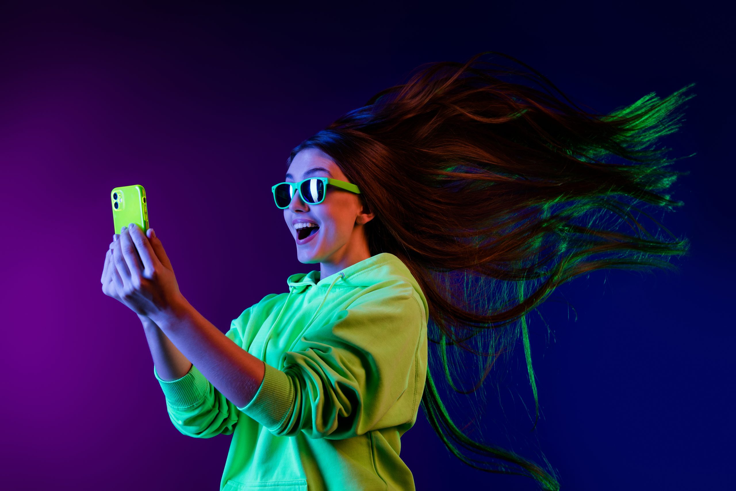 Woman wearing green hoodie and holding green phone