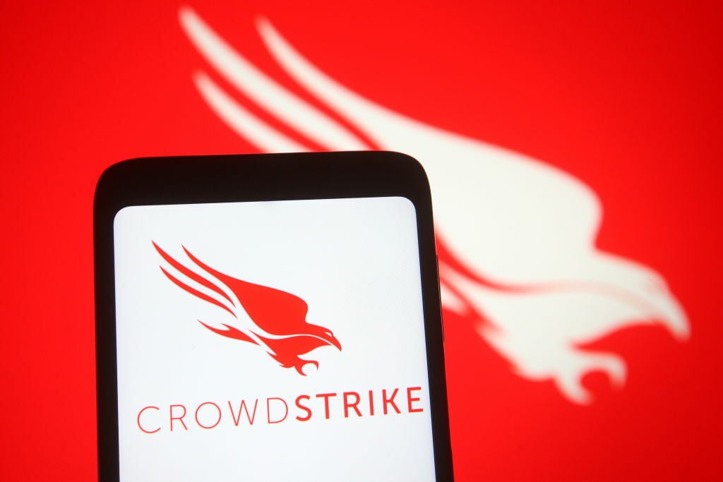  CrowdStrike logo of an US cybersecurity technology company is seen on a smartphone and PC screen.