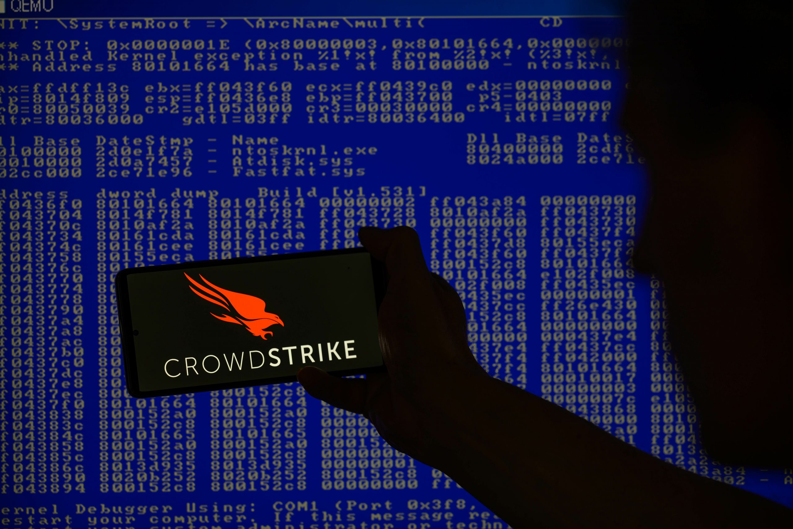 crowdstrike logo on phone in front of screen of code