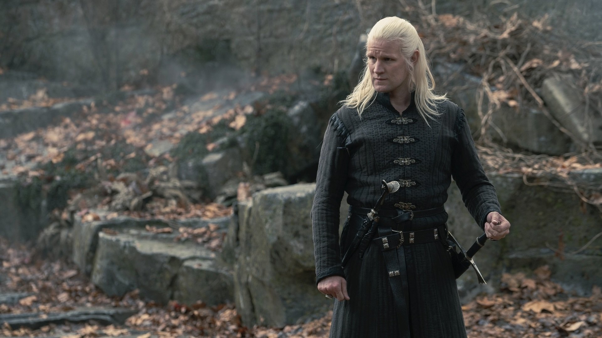 Daemon Targaryen stands in the courtyard at Harrenhal, one hand on his sword.