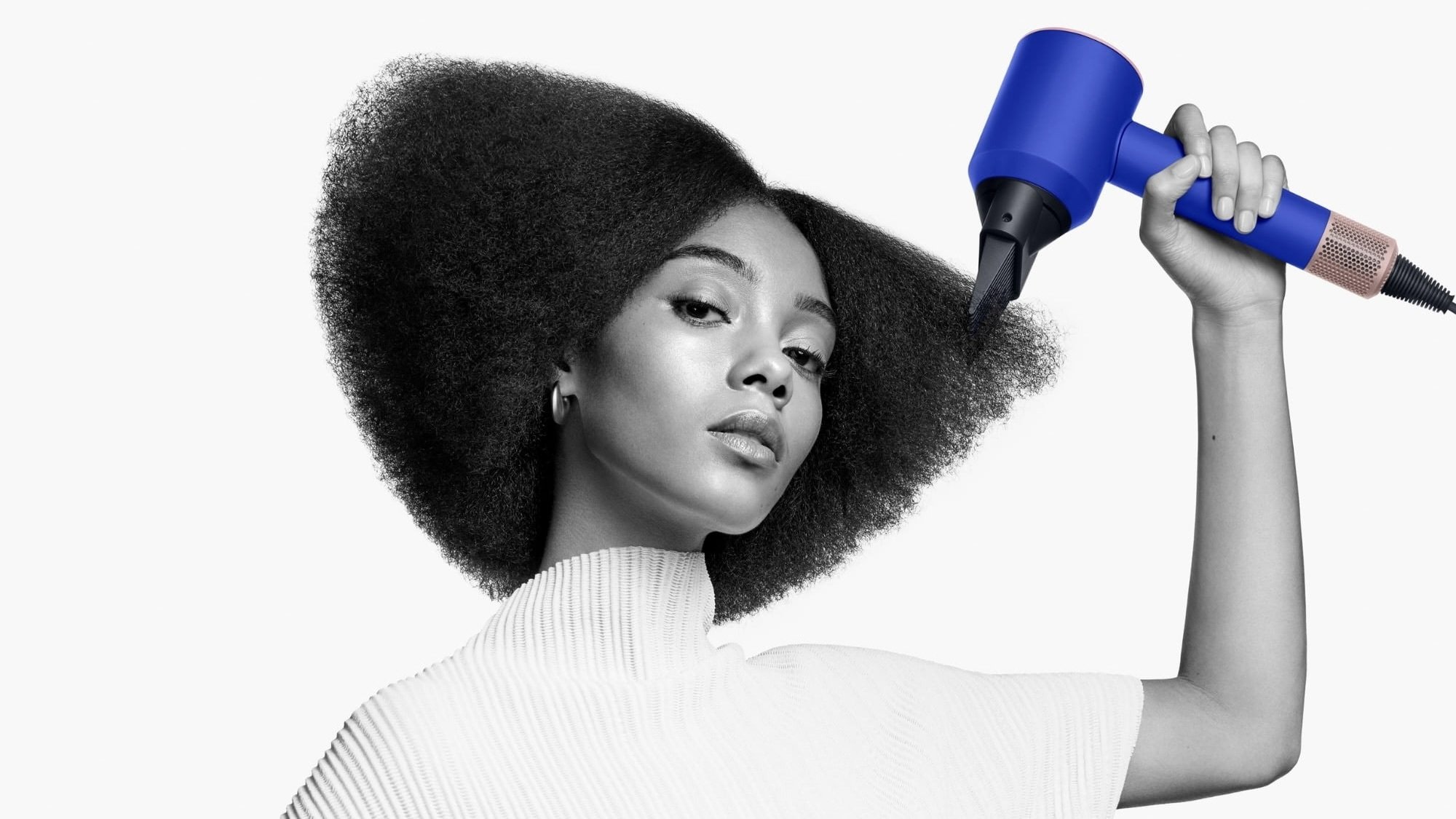 person using blue dyson supersonic hair dryer to style their hair