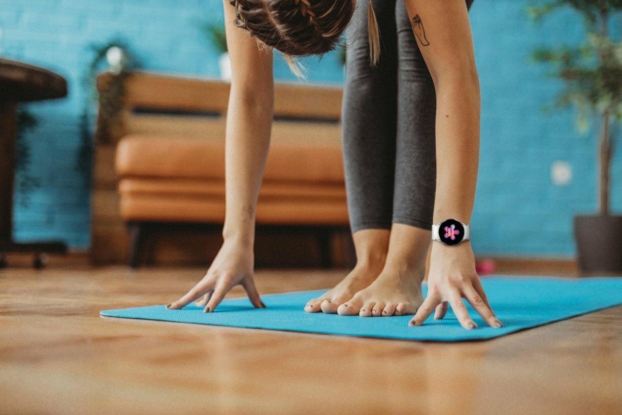 a person in a yoga position has both hands on the floor, with one wrist sporting the Samsung galaxy watch 4 