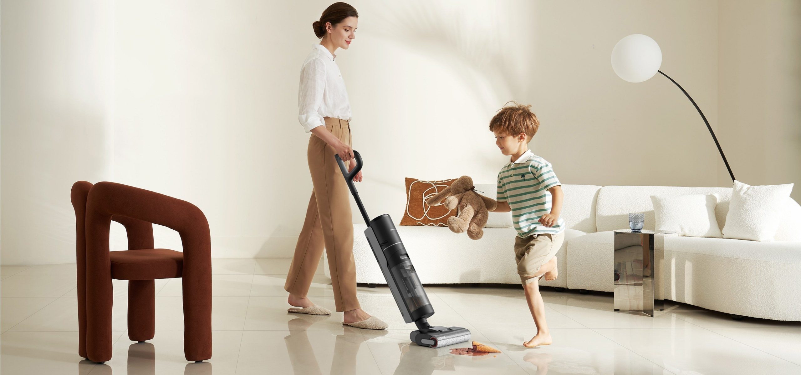 a person vacuums the floor while a child plays nearby