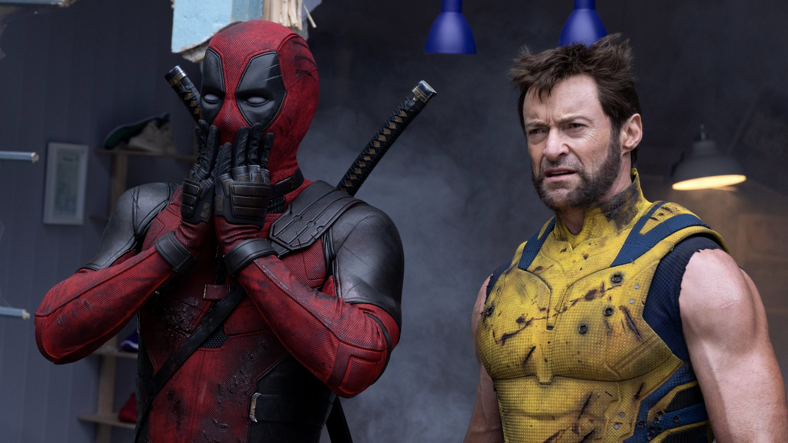 Deadpool and Wolverine standing together in a grey room.