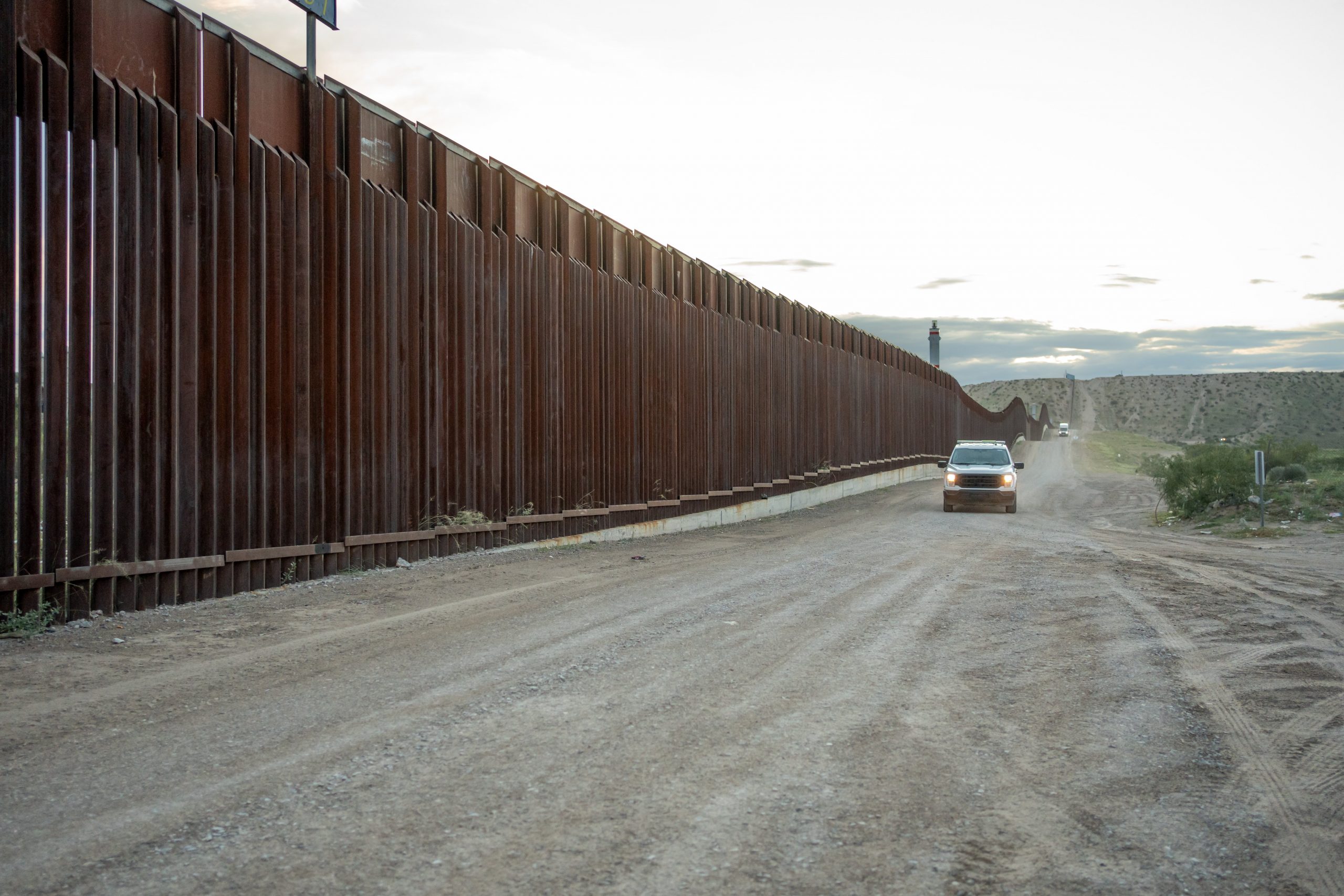 Evening Shot of Border Wall Between El Paso Texas USA and Juárez Chihuahua Texas at Puerto Anapra with US Border Patrol Vehicle in the Distance