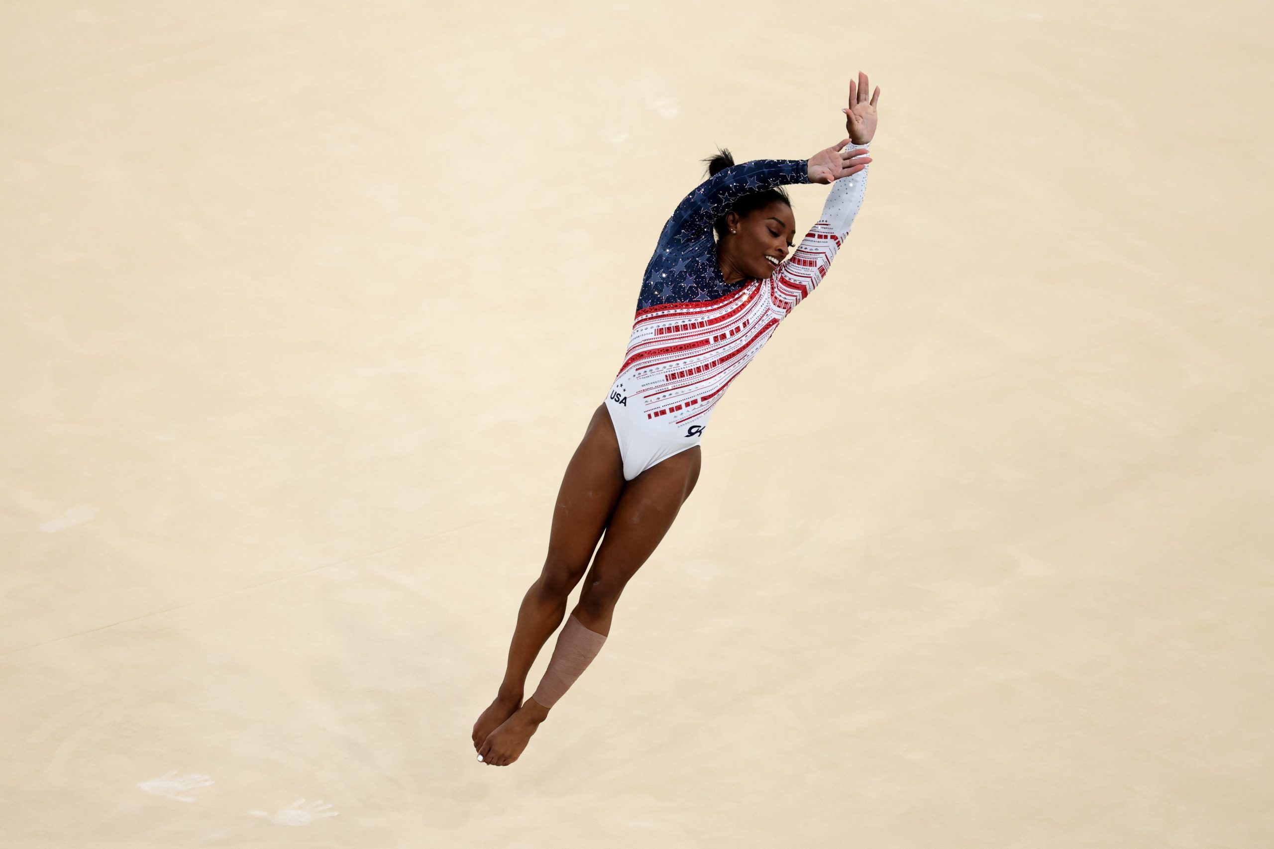 Simone Biles flies through the air during her floor routine at the 2024 Olympics. 