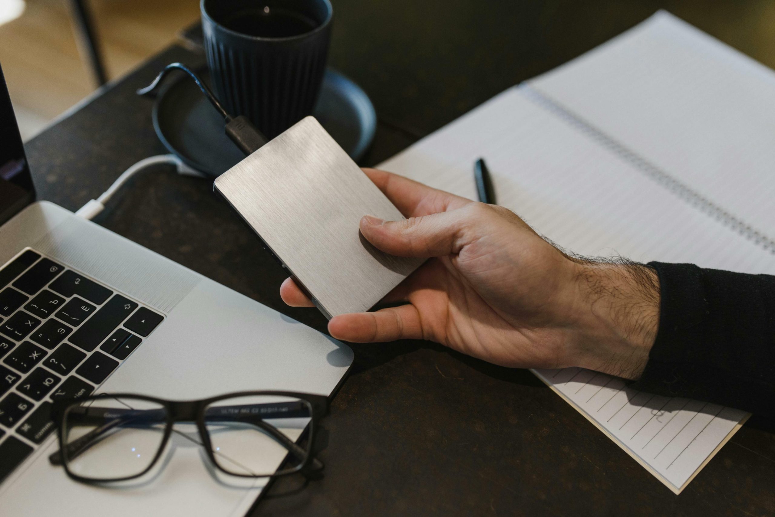 Close-up of Man Holding a Hard Drive Connected to His Laptop