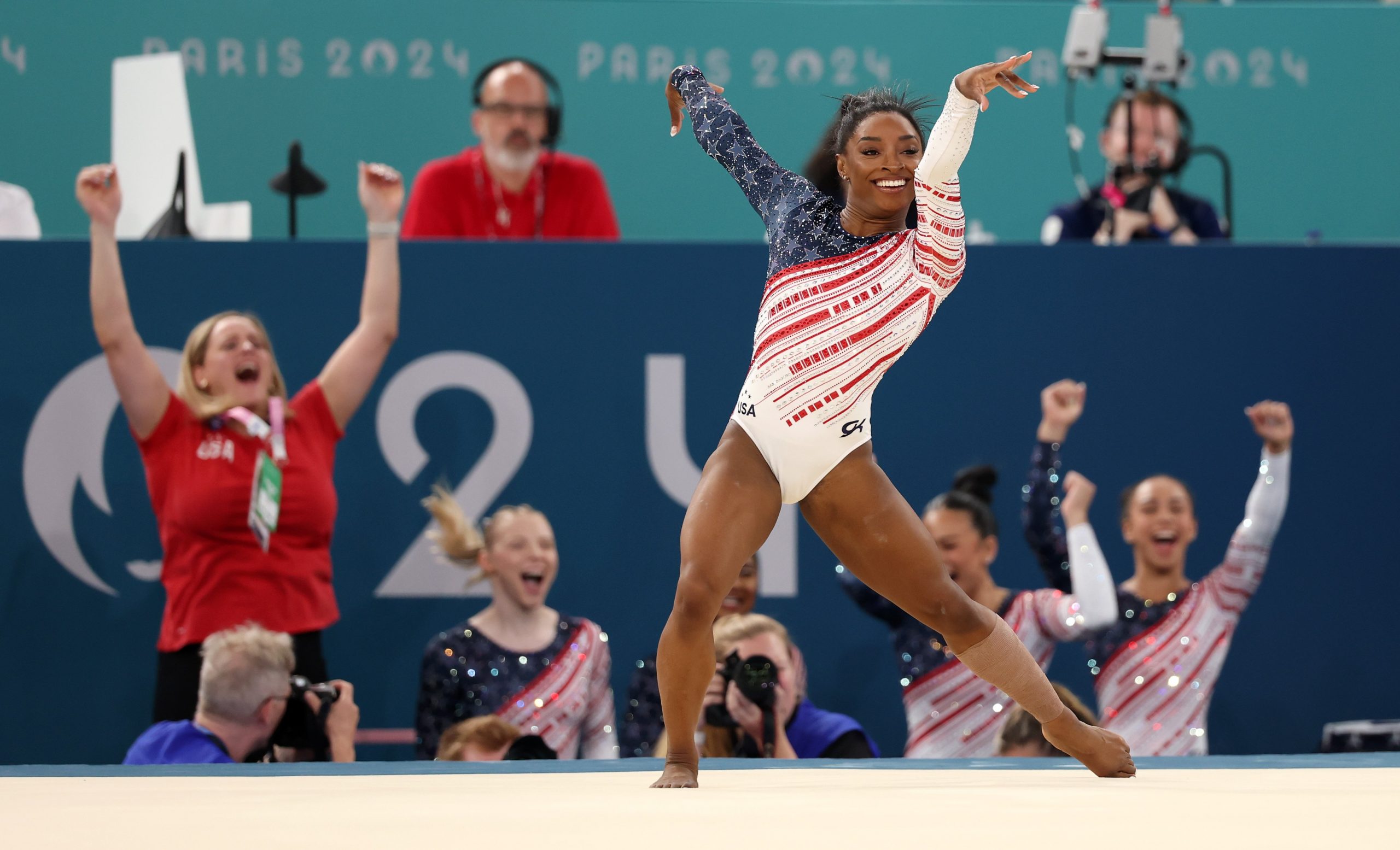 simone biles posing doing her floor routine with team in background