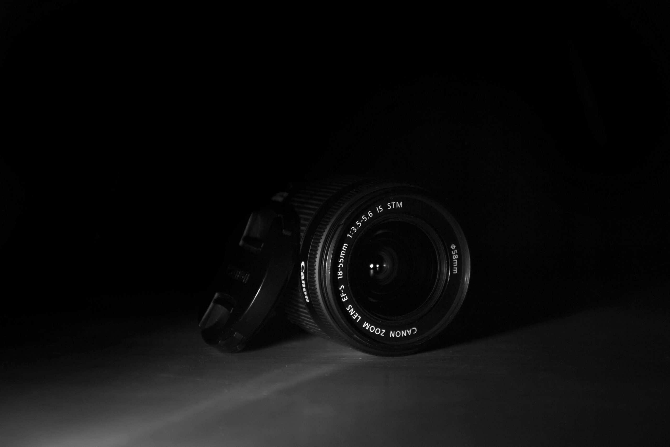 A camera lens emerges from the dark.