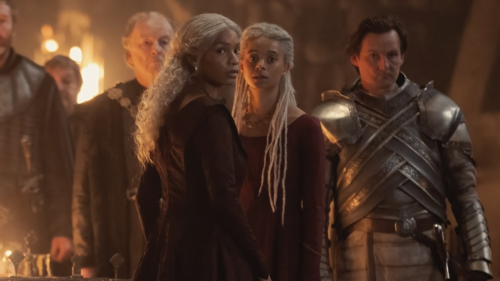 Baela and Rhaena Targaryen stand in a hall in Dragonstone, surrounded by knights and lords.