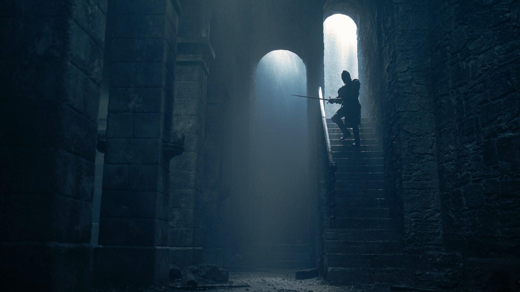 Daemon Targaryen descends a flight of stairs in the darkened ruins of Harrenhal, holding a sword aloft.