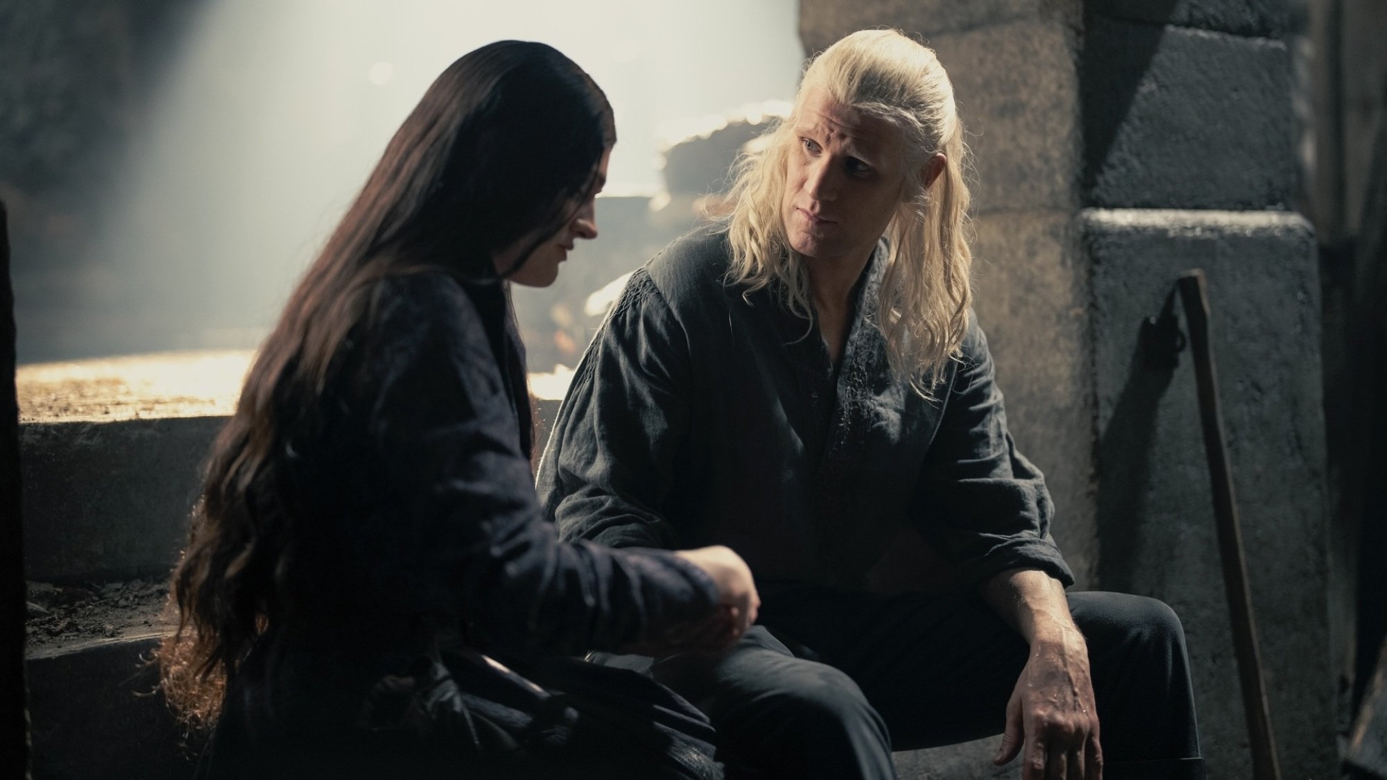 Alys Rivers and Daemon Targaryen sit on steps at Harrenhal; she is tending to one of his injured hands.