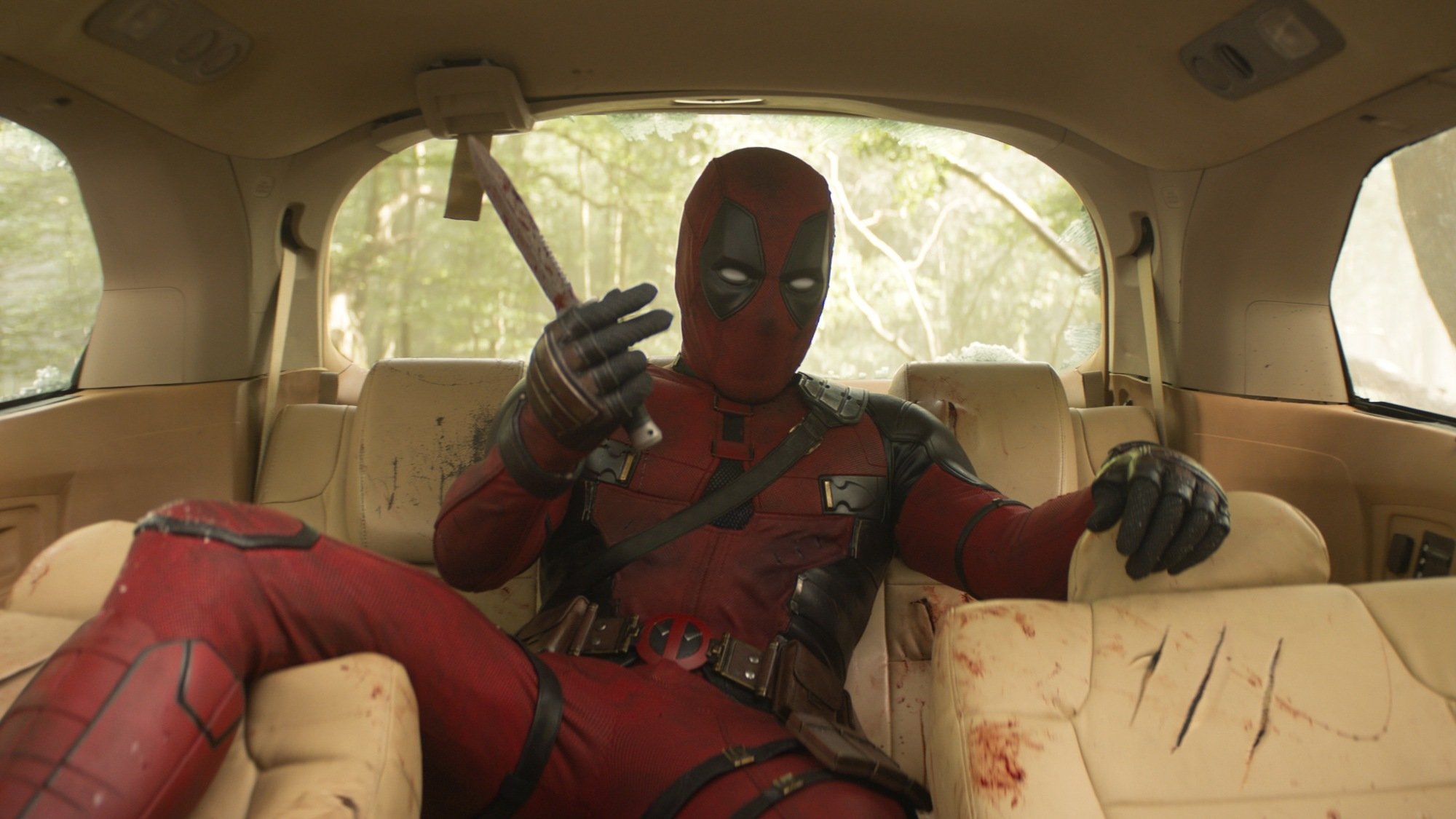 Deadpool is beaten and bloody in a Honda Odyssey. 