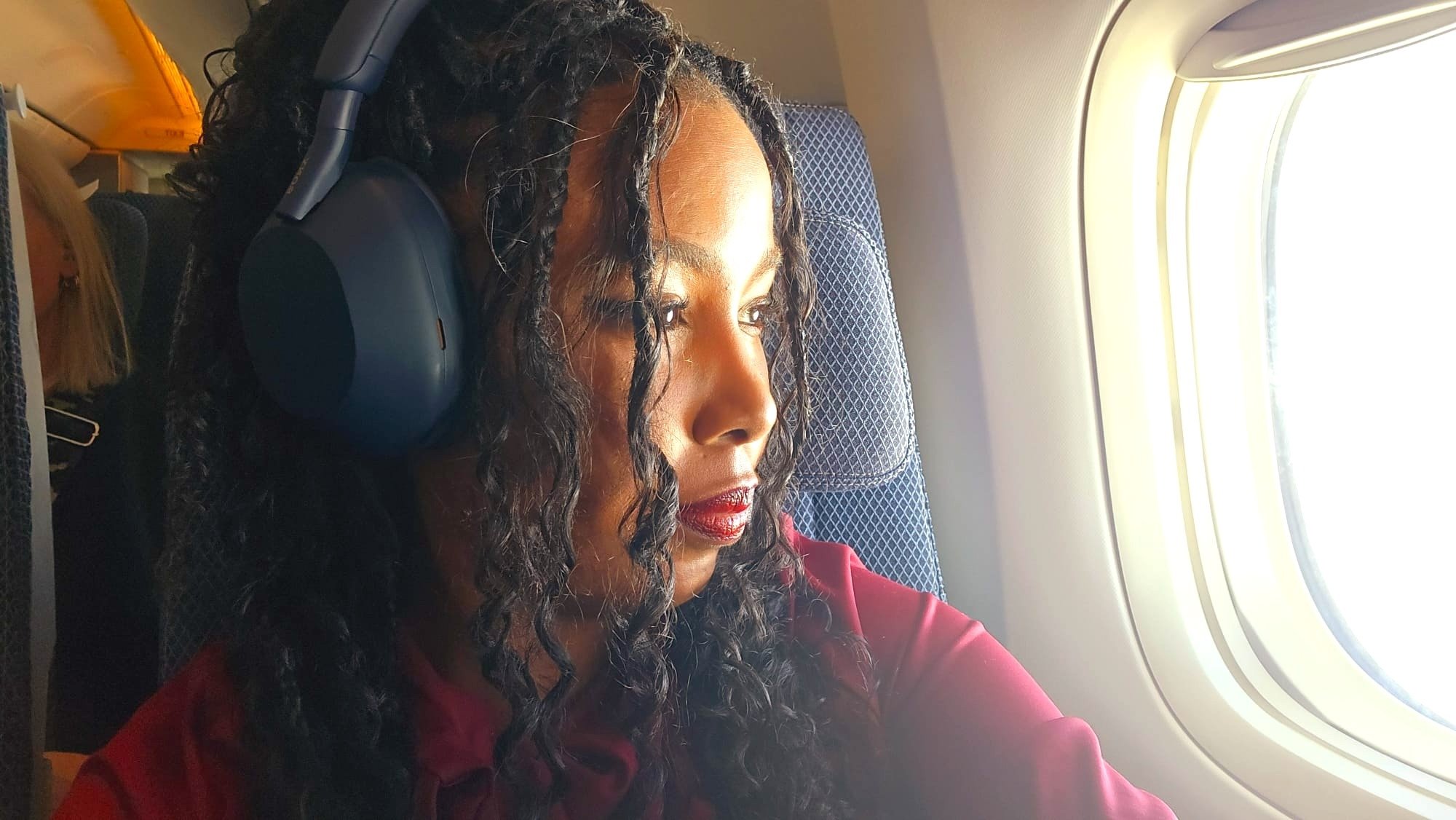 Woman wearing Sony WH-1000XM5 headphones on a plane