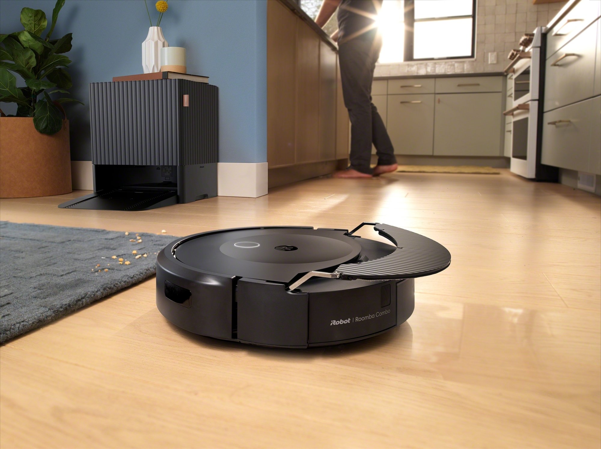 Roomba vacuuming hardwood floor holding retractable mop overhead