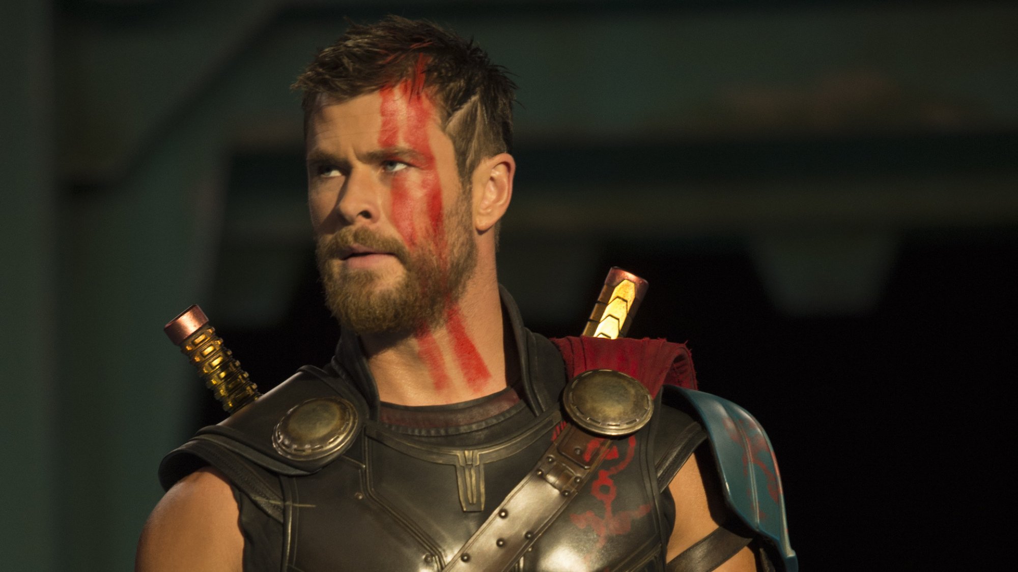 A closeup of Chris Hemsworth as Thor Odinson, with short hair and red war paint on his face.