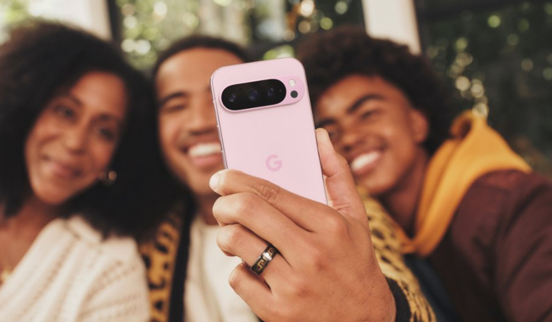 Three people taking a selfie on pink Google Pixel 9 Pro smartphone