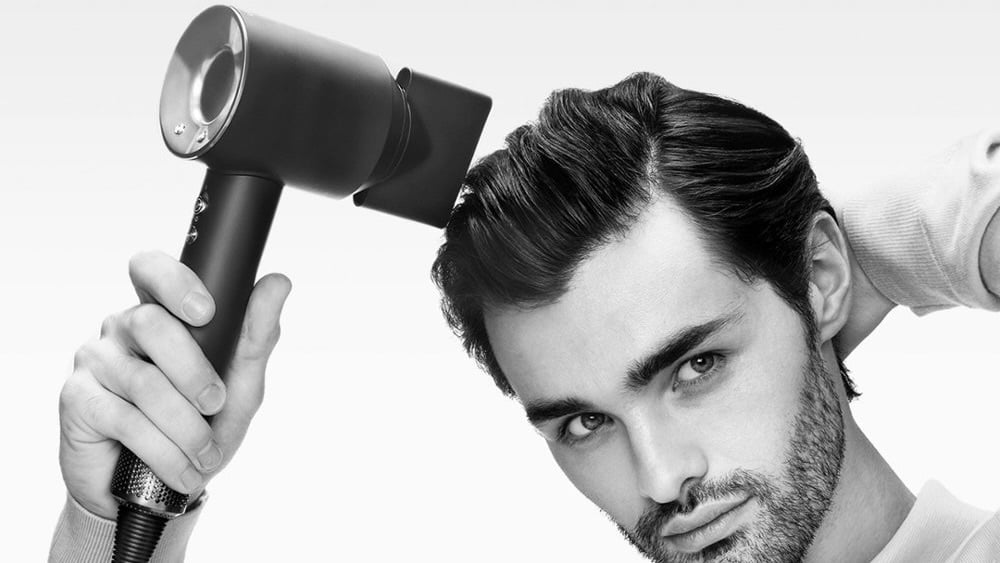 man drying his hair with dyson supersonic origin