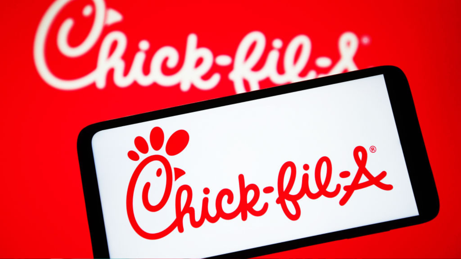 The Chick-fil-A logo is seen on a smartphone and on a PC screen.