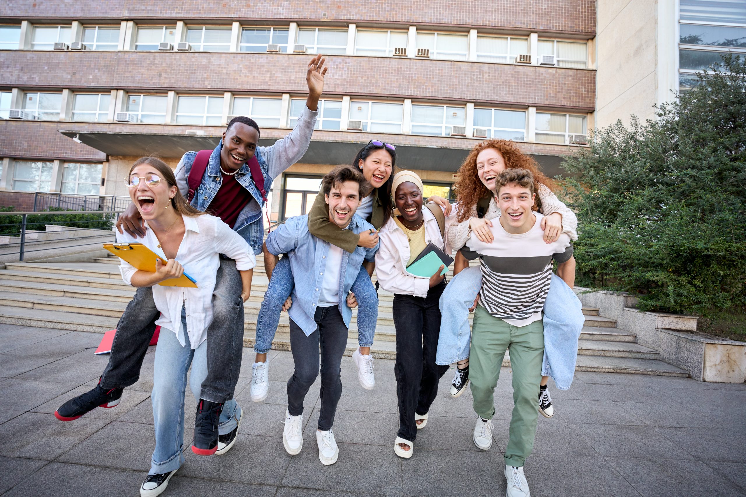 a group of young adults walk toward the camera while looking happy