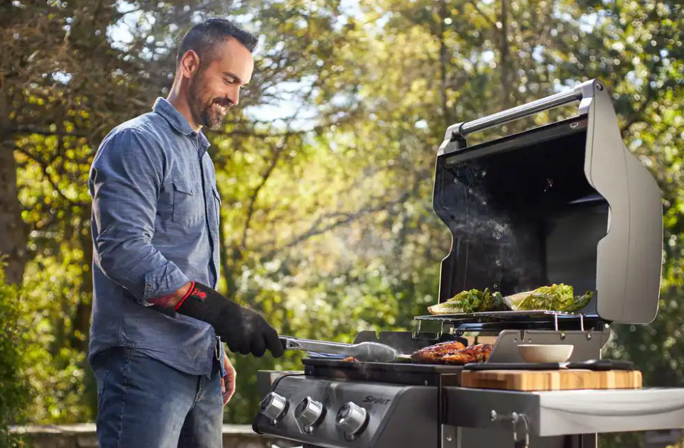 A man cooks out on a Weber grill