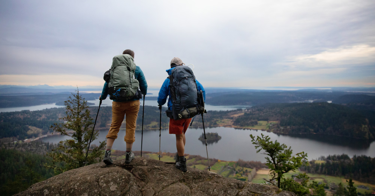 two men looking off a cliff into the distance 