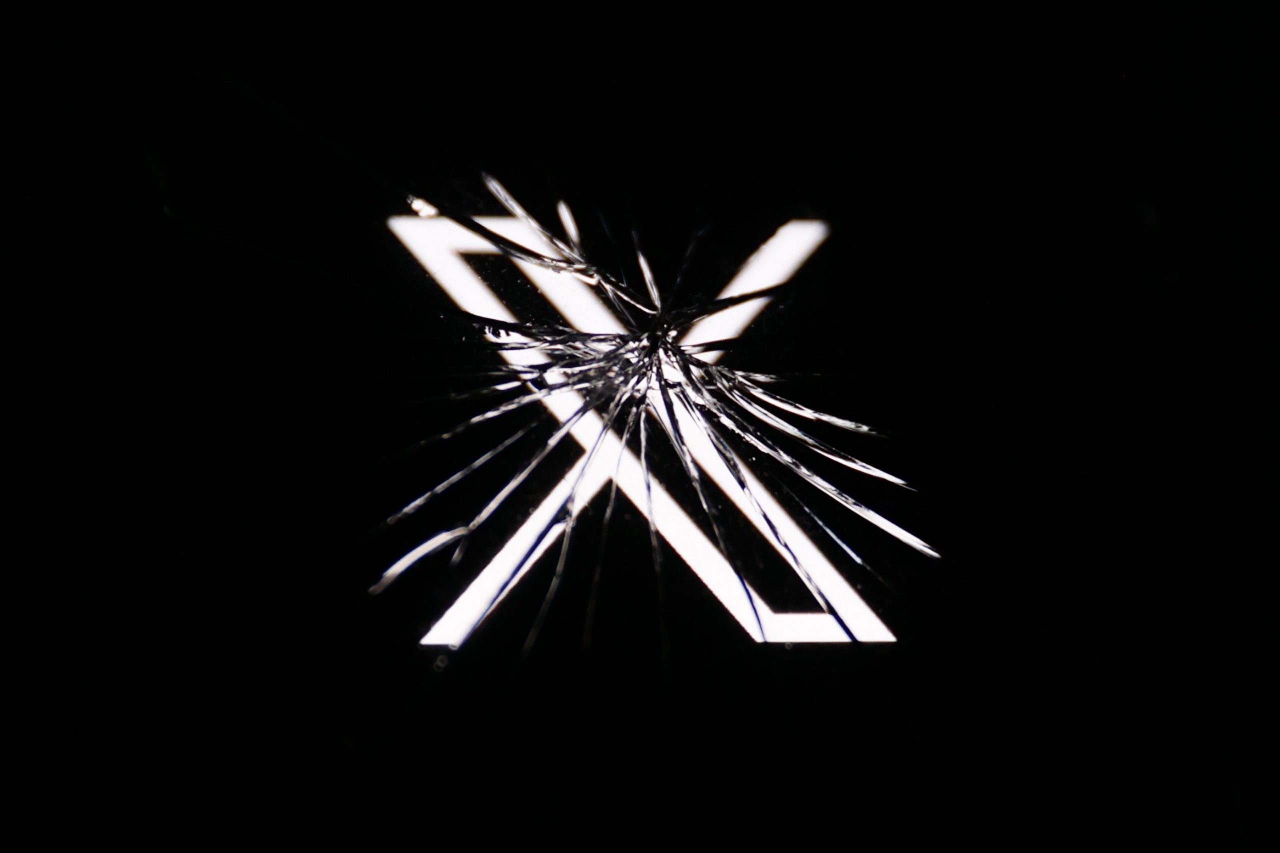 X logo behind broken glass