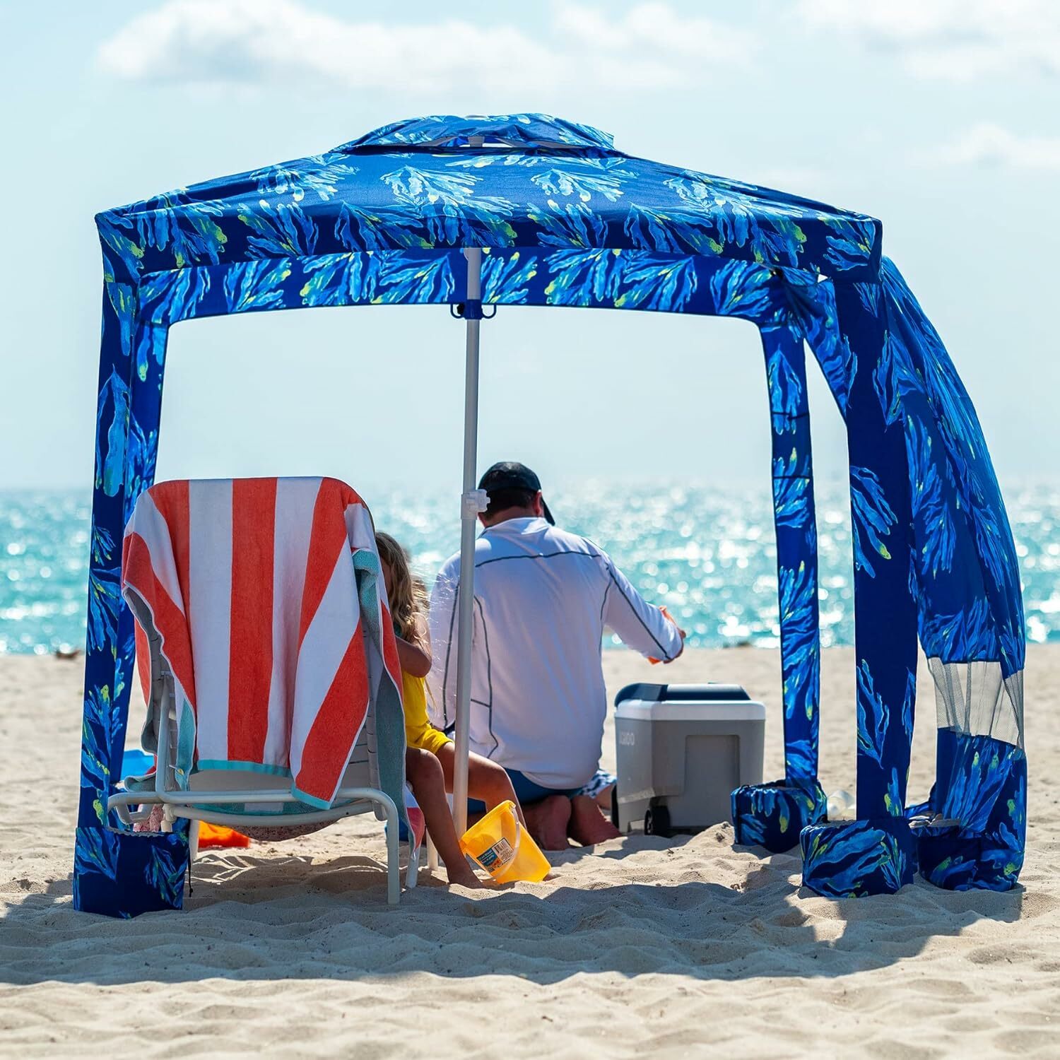 A man sits out at the beach under a beach cabana 