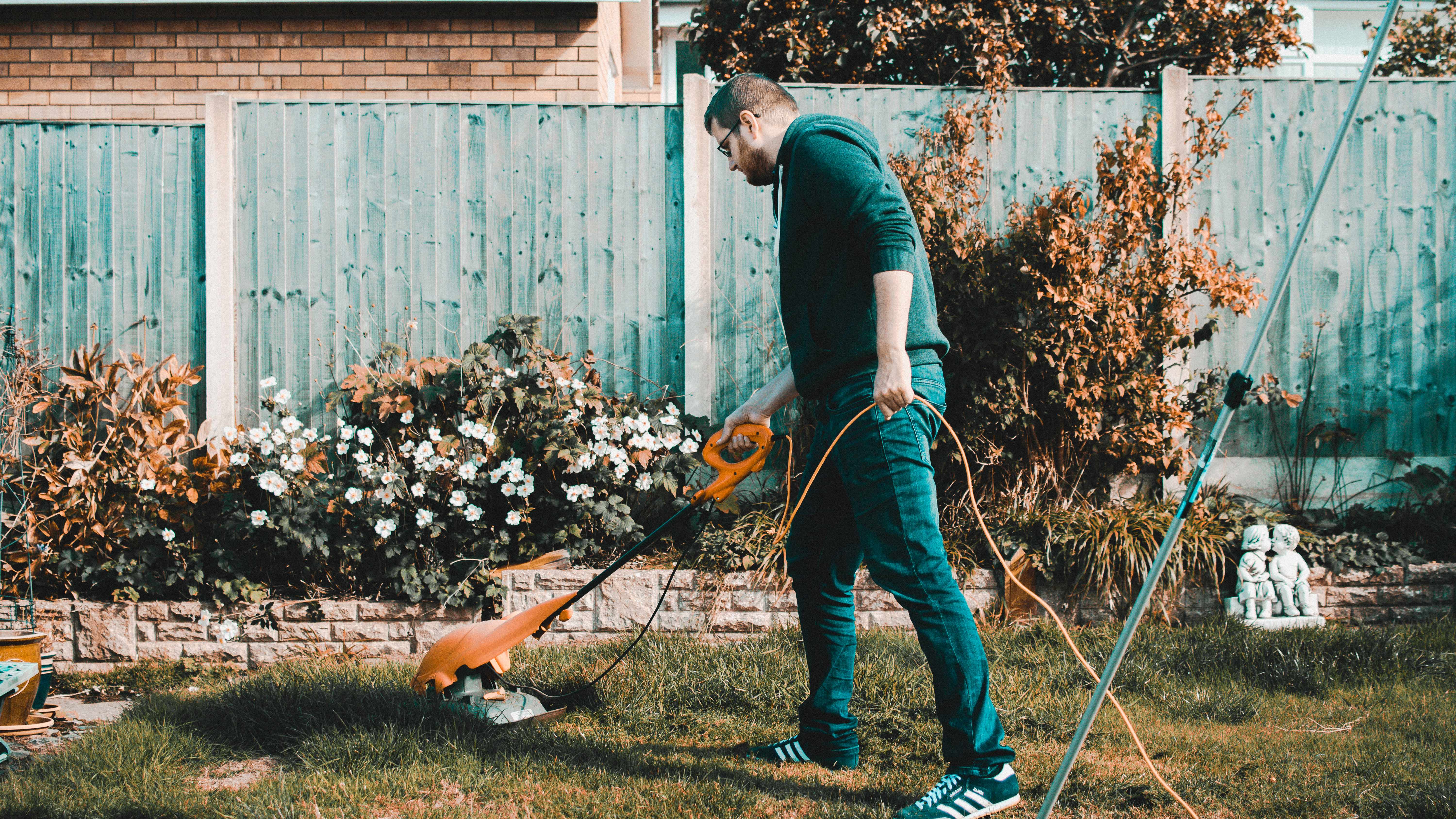 A man strimming his garden lawn