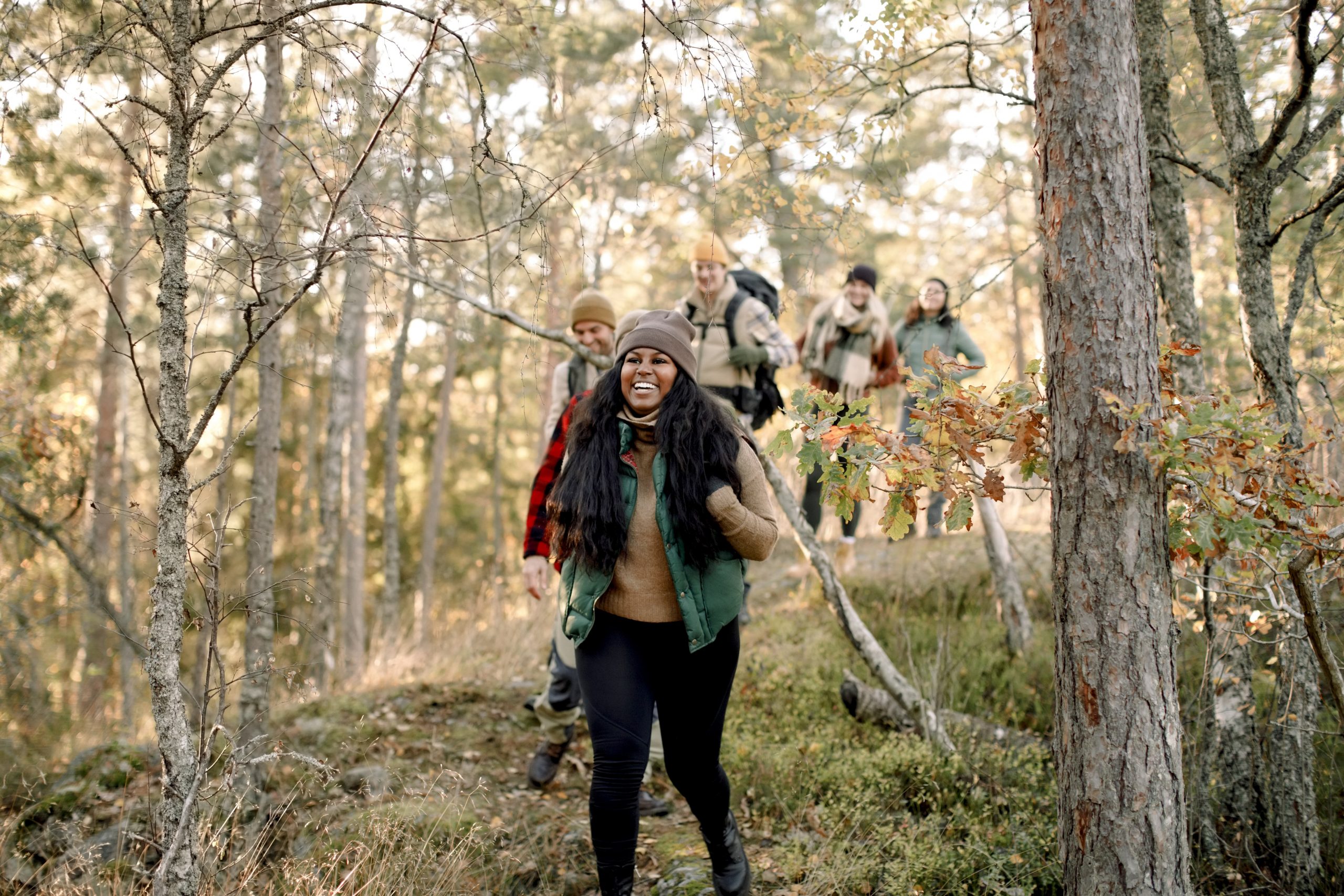 a group of people hiking in nature while all wearing packs and fall clothing