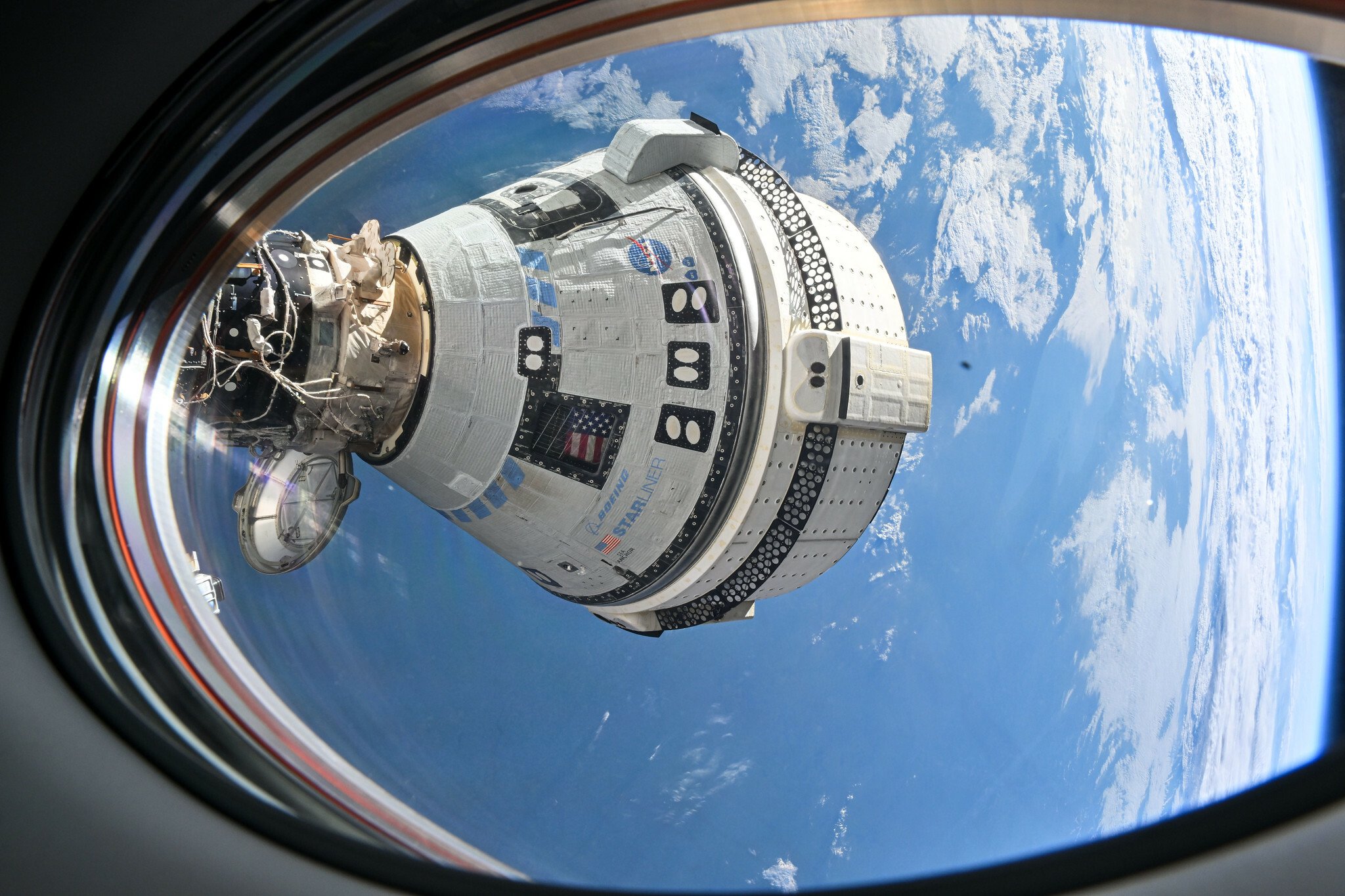 Starliner flying in space while docked at the International Space Station