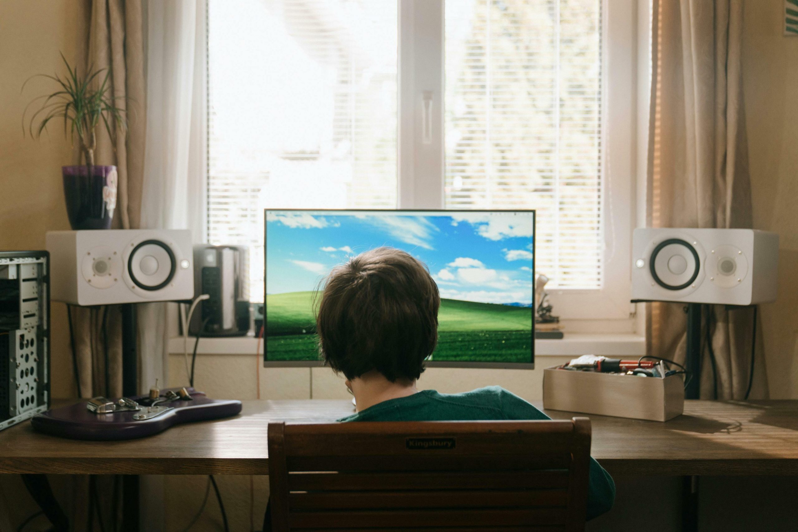 boy sitting in front of desktop computer with external speakers