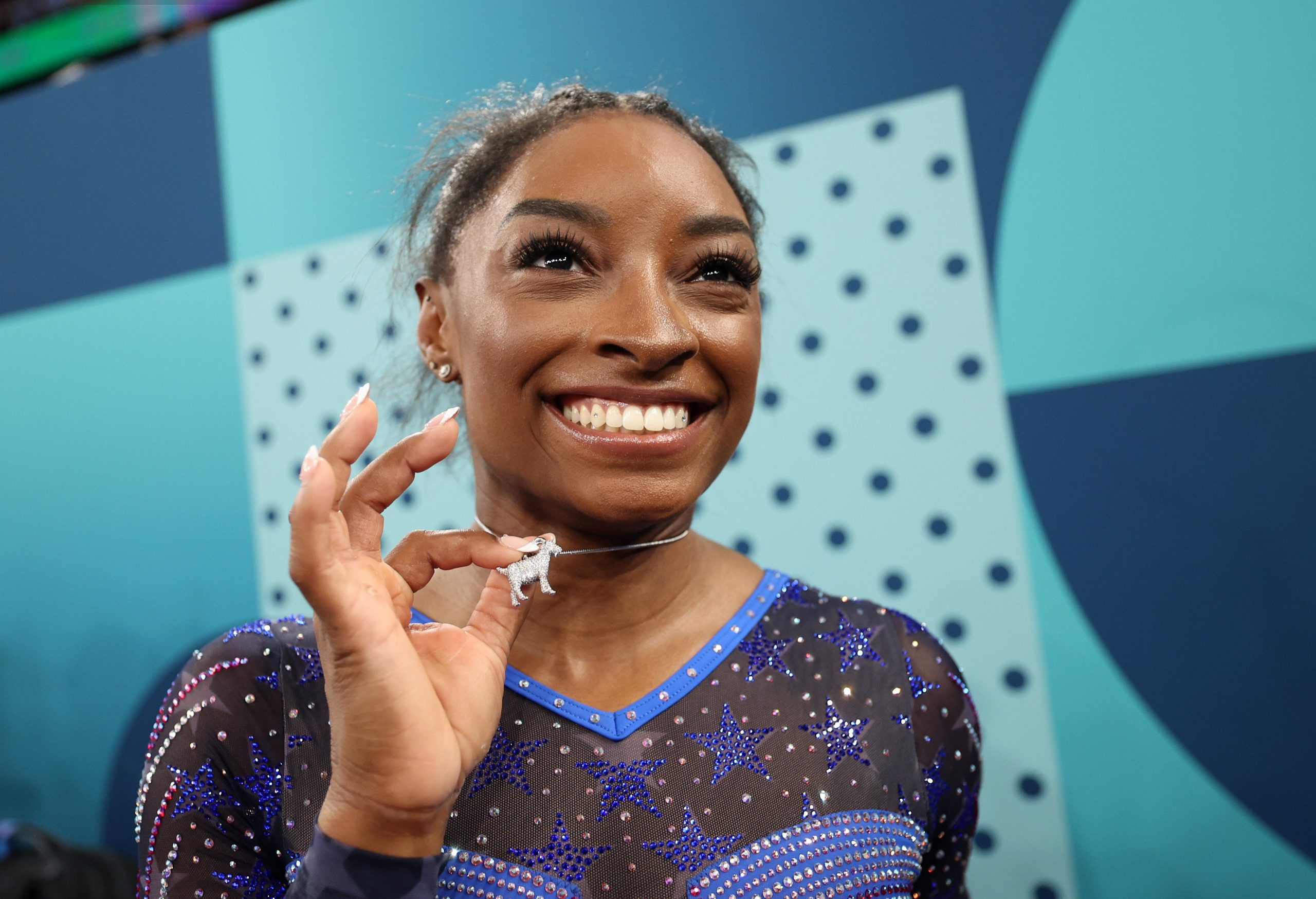 simone biles holding a necklace with sparkly goat