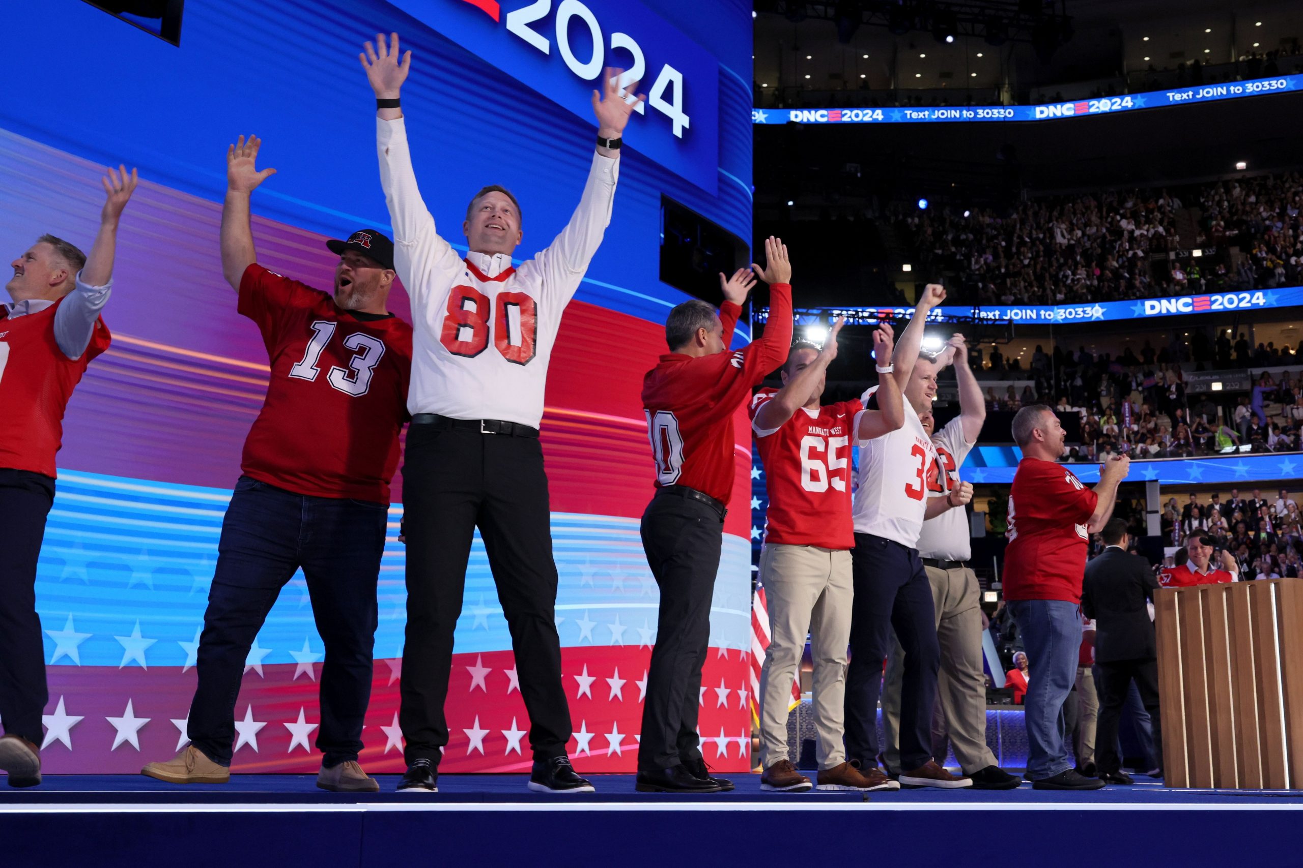 grown men in football jerseys on the DNC stage, all former players for Tim Walz