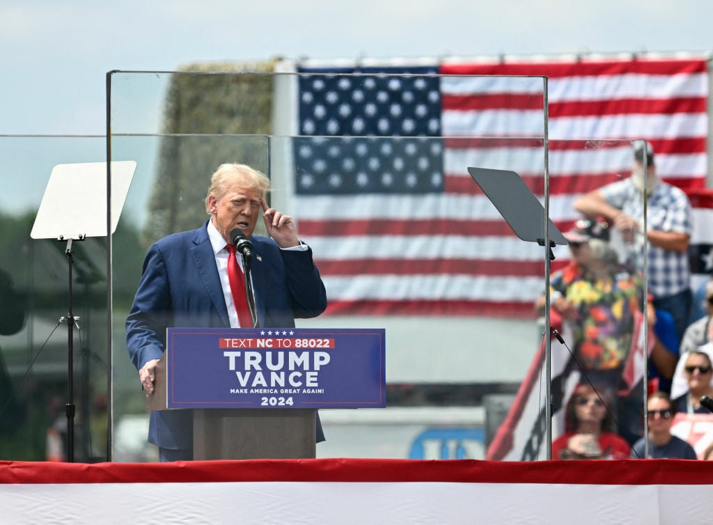 Donald Trump behind bulletproof glass at a campaign rally in 2024