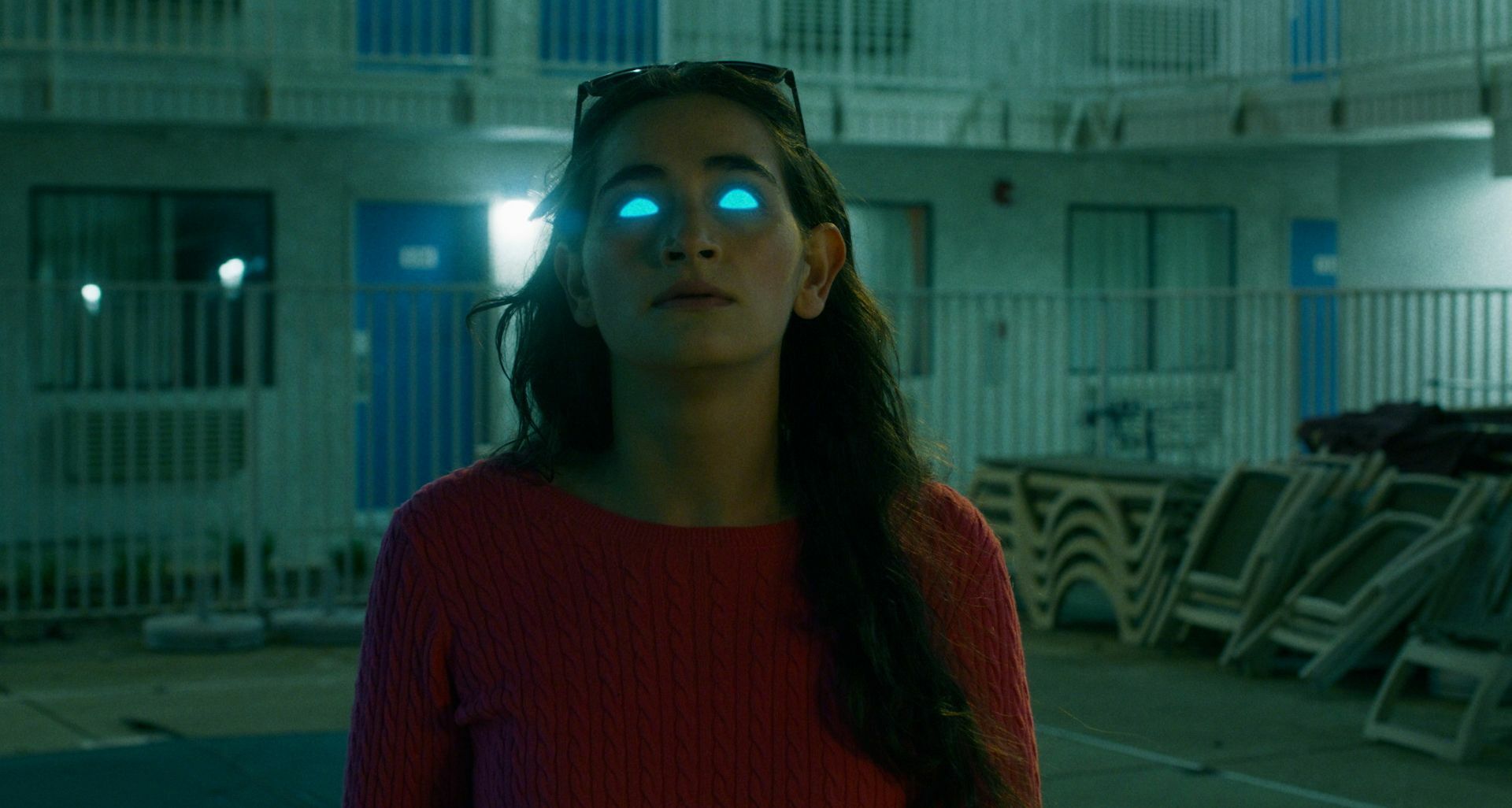 A white woman with eyes glowing blue, alien-like. 