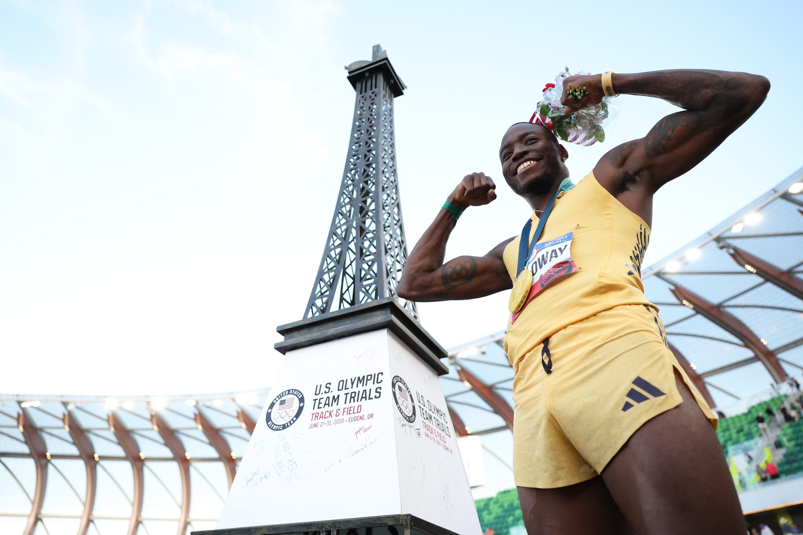 Grant Holloway poses with the gold medal in front of a miniature Eiffel Tower 