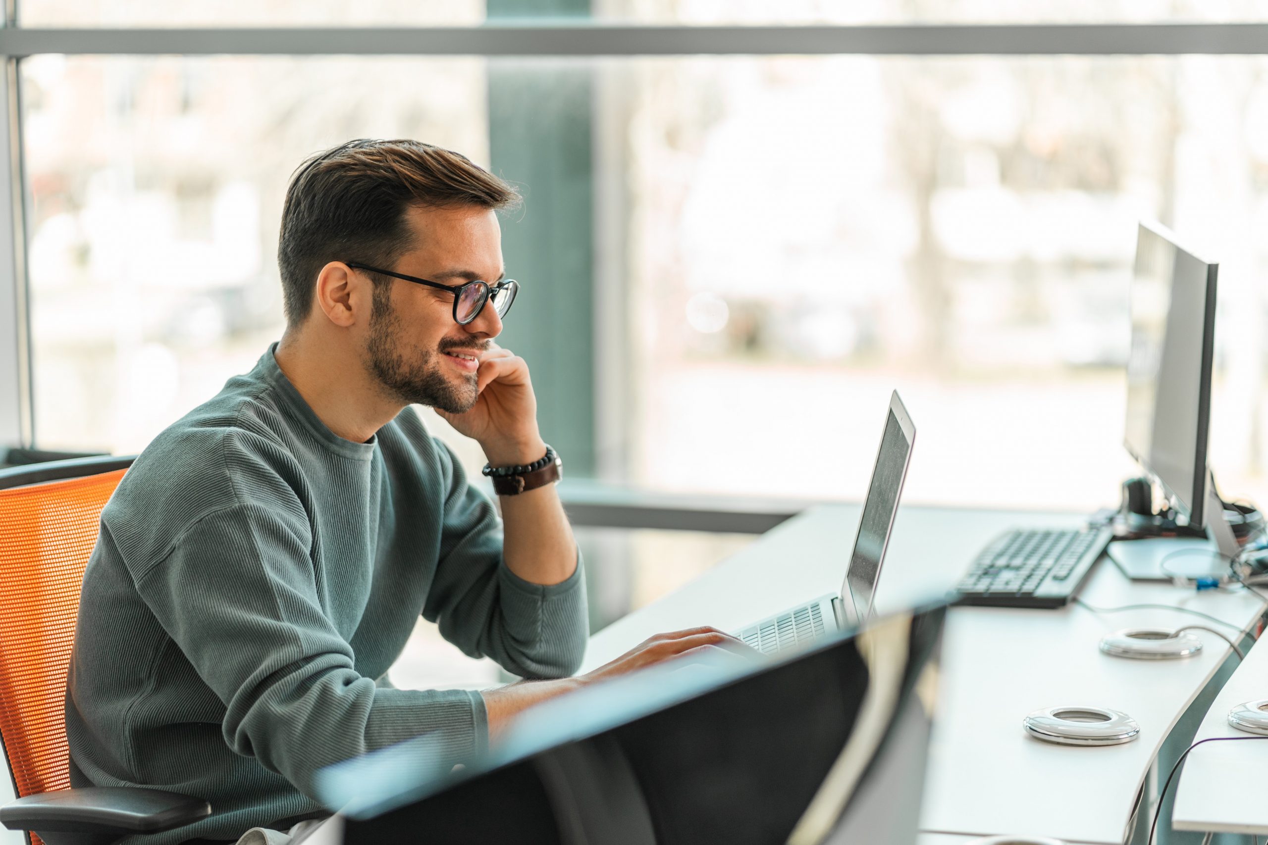 young man sitting at computer and smiling