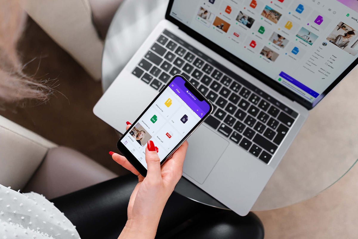 Woman holding smart phone in front of a computer