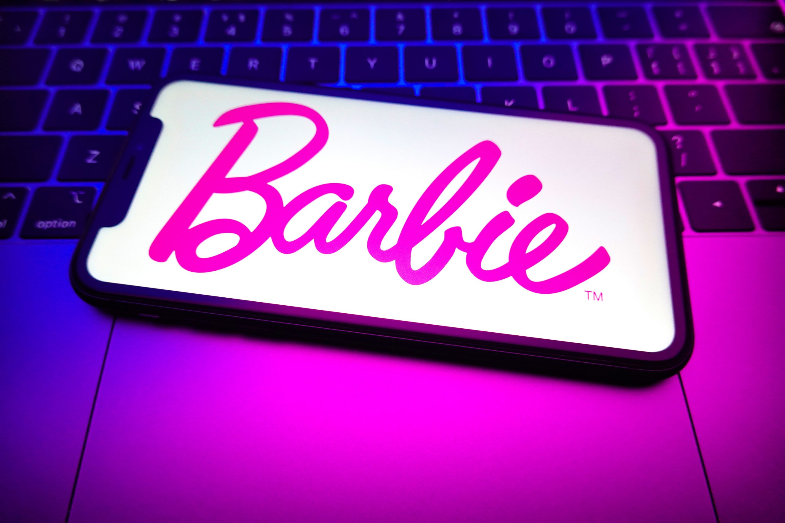 A Barbie logo is displayed on the screen of a smartphone.