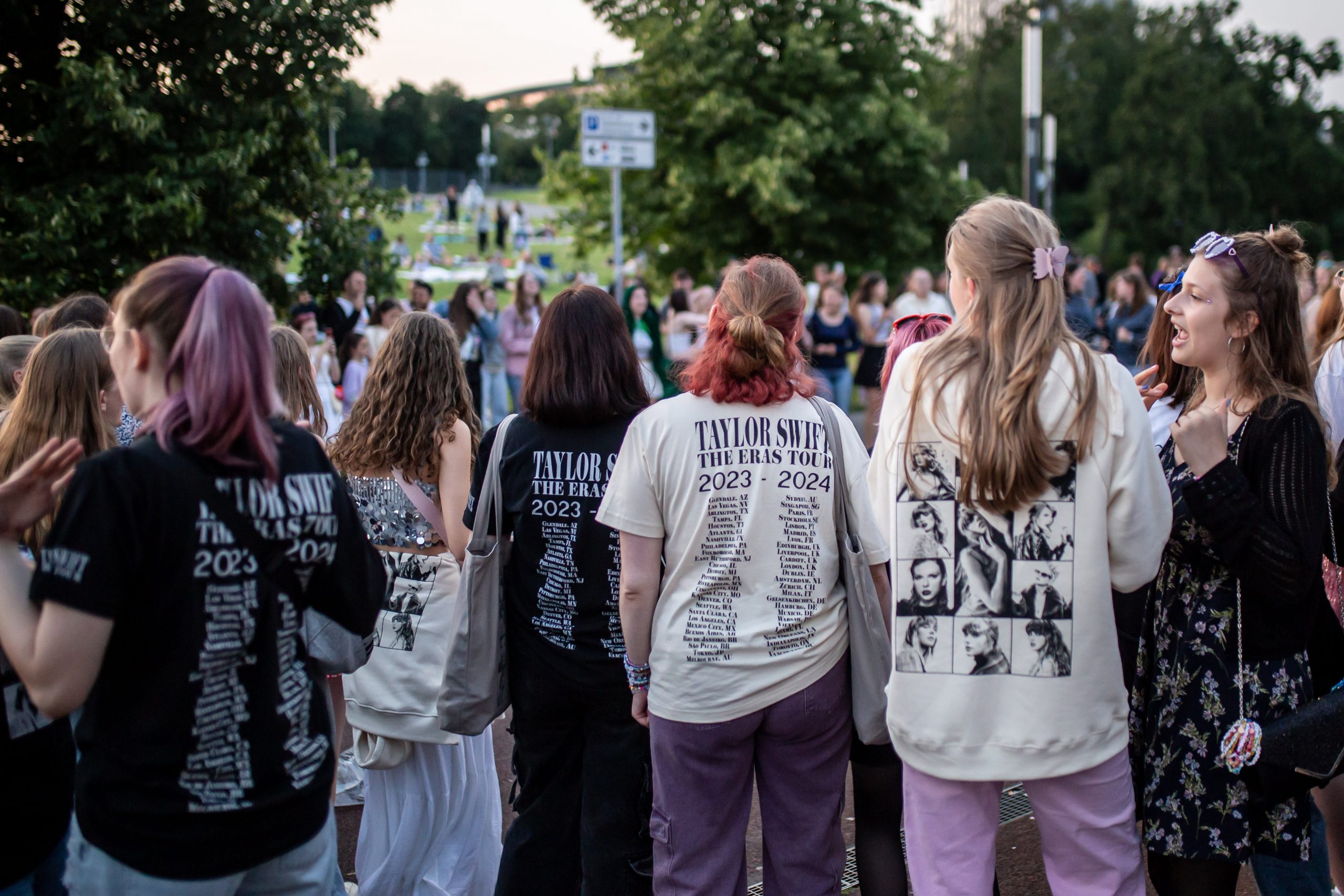 Taylor Swift fans decked out in merch standing in a crowd. 