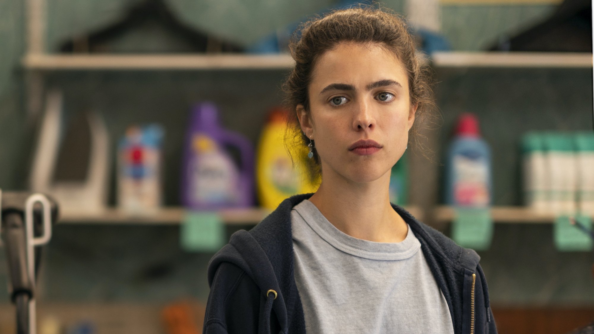 A young woman looks concerned while standing in a laundry room. 