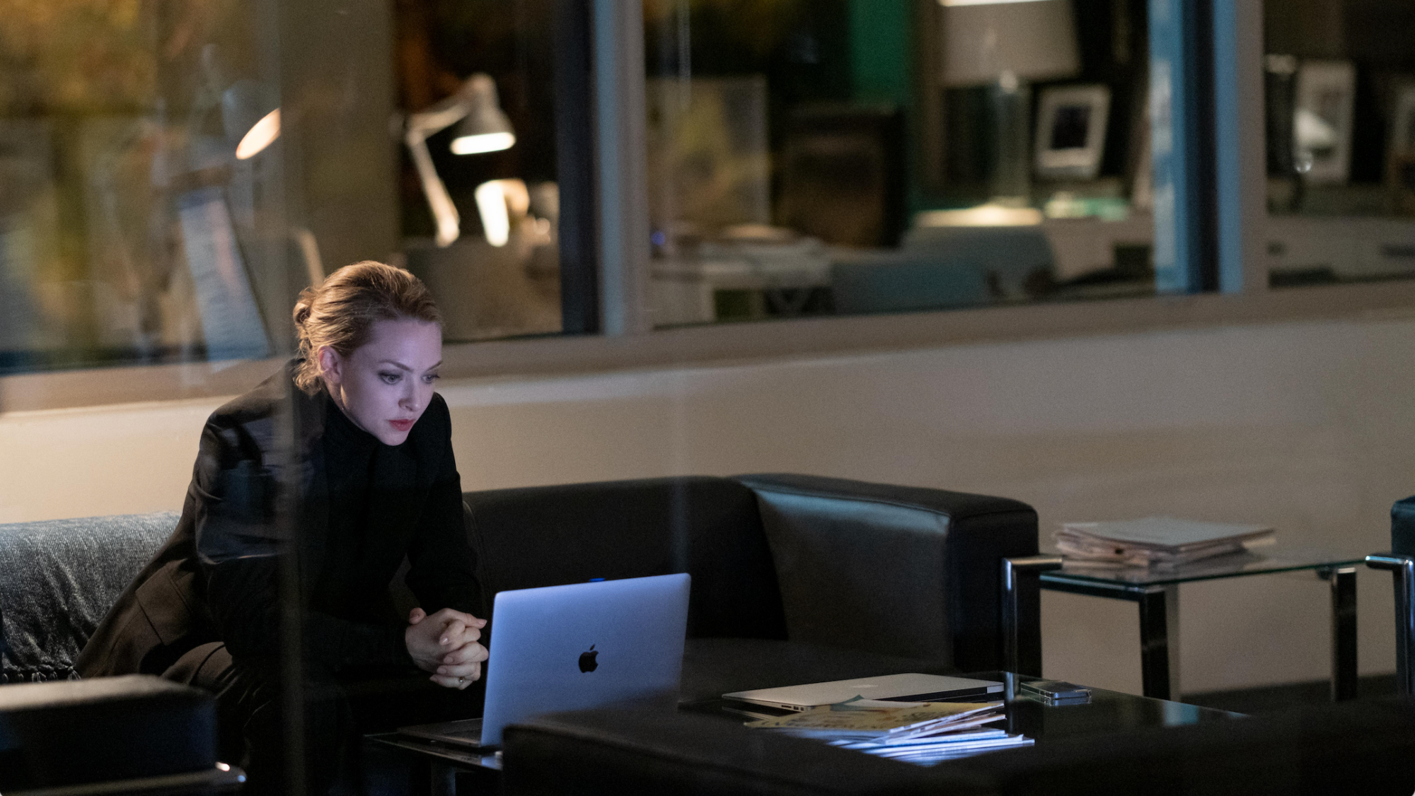 A woman works on her laptop in her office at night. 