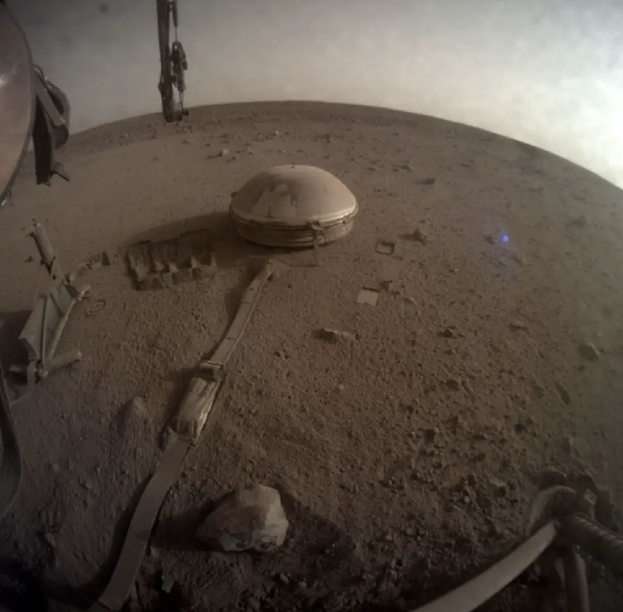 A view of the InSight lander's dust-covered seismometer on the Martian surface.