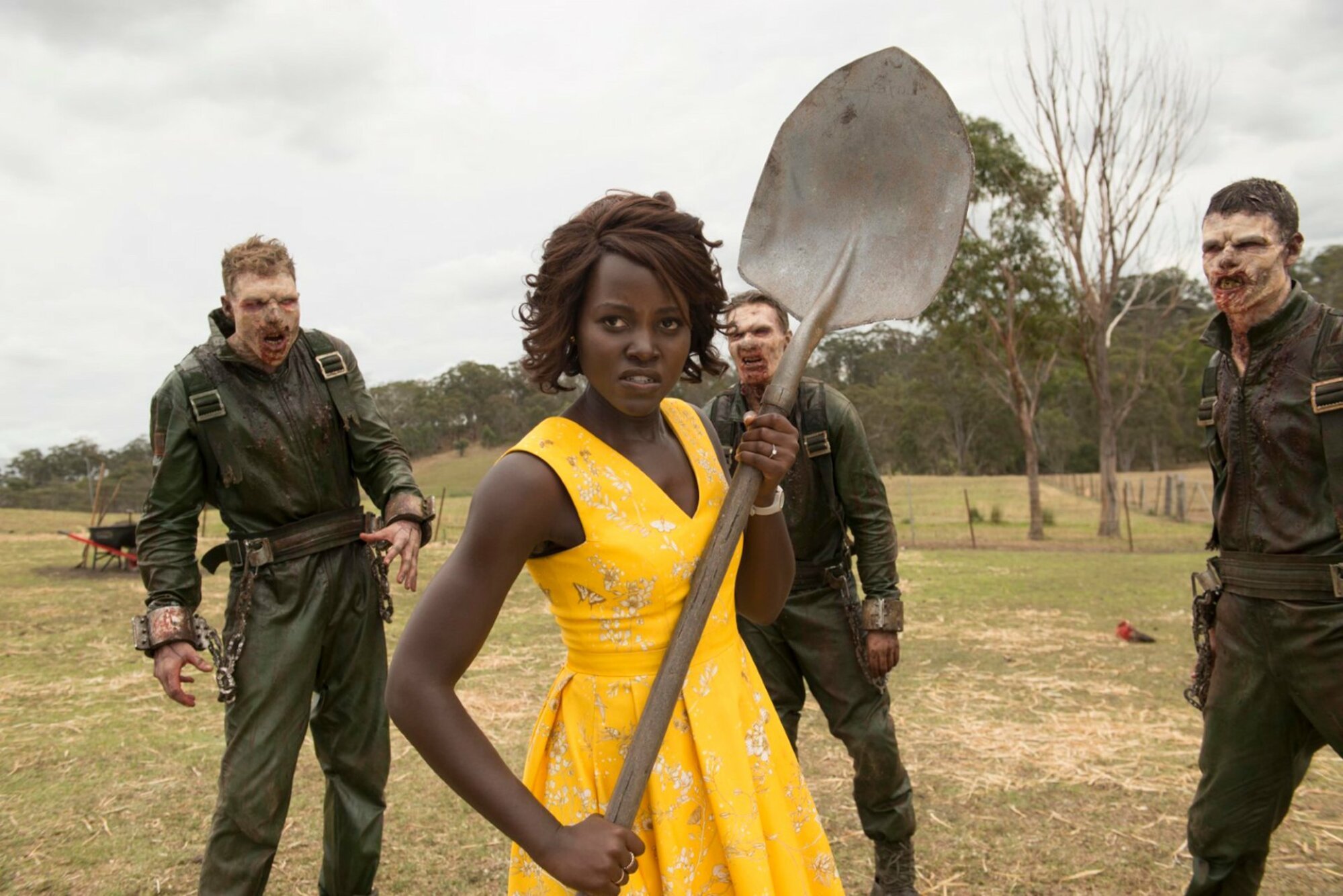 Lupita Nyong'o holds a shovel while surrounded by zombies in "Little Monsters."